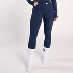 A person wears high-waisted navy blue leggings paired with white crew socks against a plain light grey background.