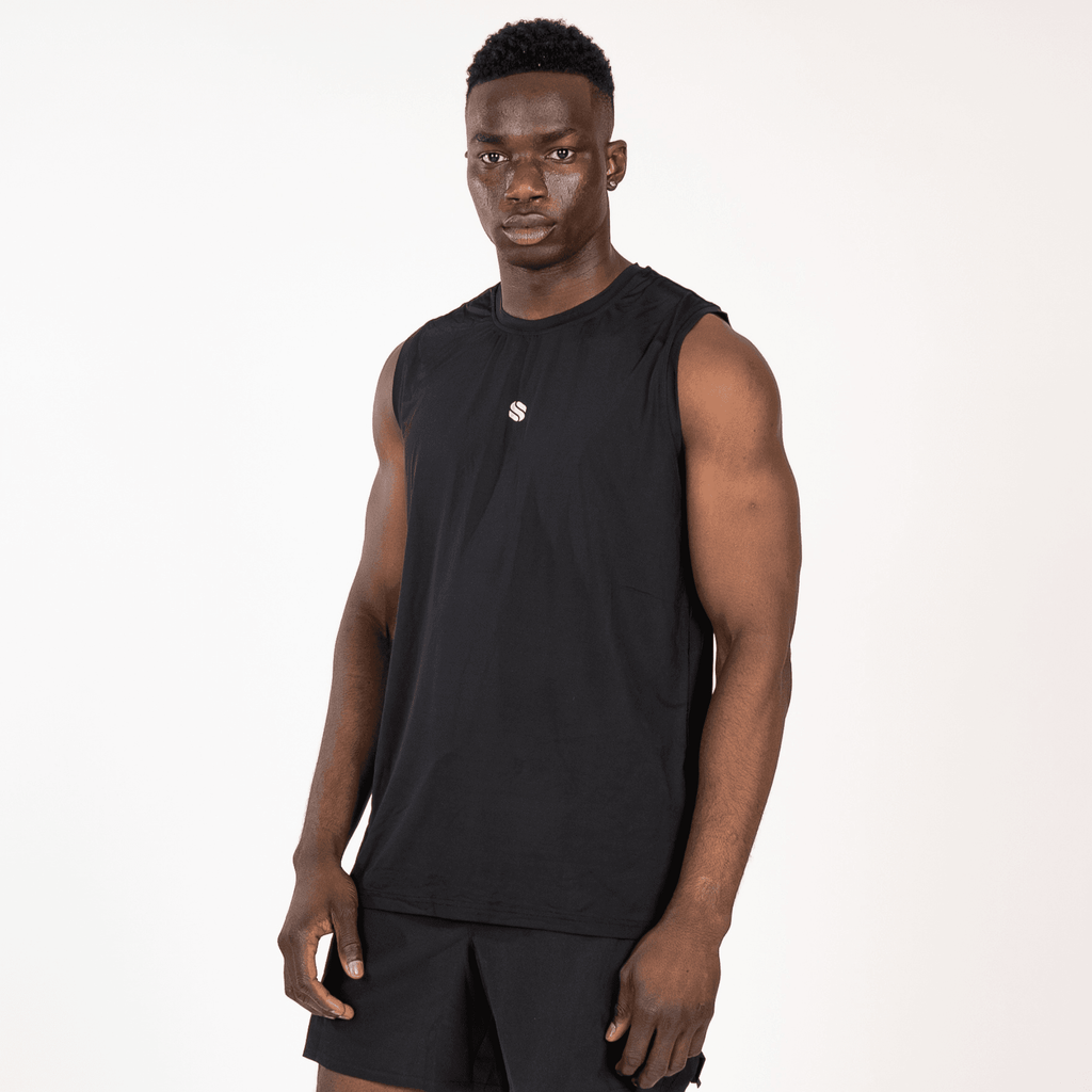 A man wearing a plain black sleeveless workout tank top and matching black athletic shorts stands against a white background.